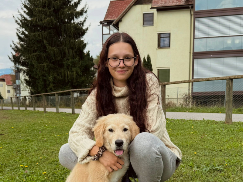 Bild von Jessica mit einem jungen Hund auf einer Wiese.