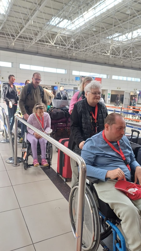 Urlaubsgruppe steht in Schlange beim Check-In am Flughafen